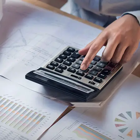 A person using a calculator on top of accounting paperwork.