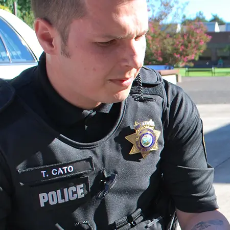 A police officer kneels down in front of a police car.